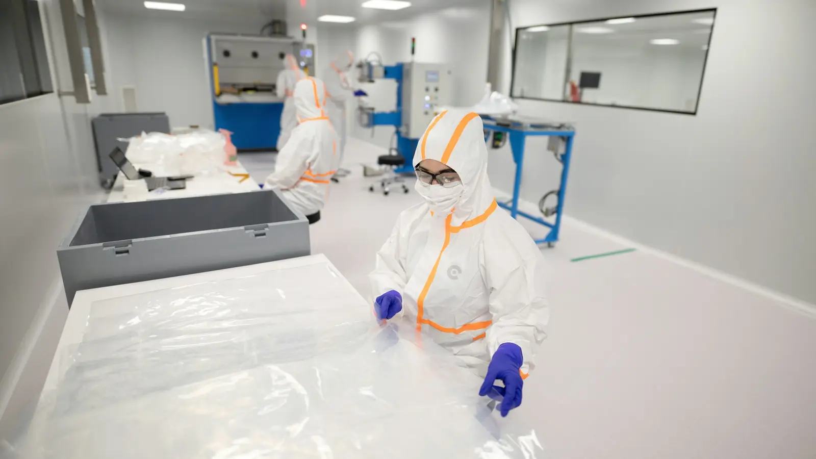 Technicians in protective suits working in a cleanroom